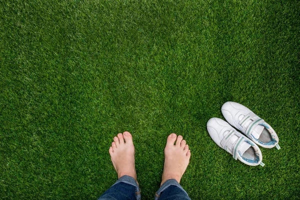 Pés descansando na grama verde com tênis — Fotografia de Stock