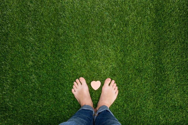 Küçük kalp ile çimenlerin üzerinde duran ayak — Stok fotoğraf