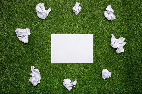 Witte vellen papier met cramled bladen op het gras — Stockfoto