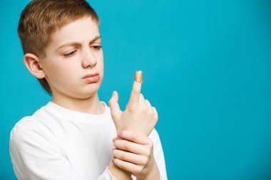 Yapıştırıcı ile Beyaz giysili mutsuz çocuk onun parmağına alçı