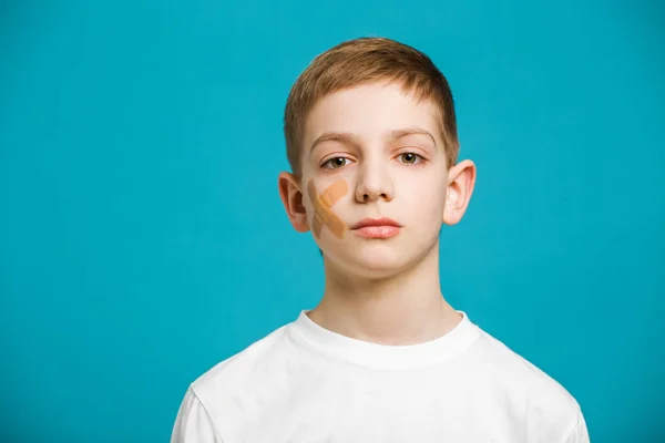 Retrato de un niño con yeso adhesivo en la mejilla —  Fotos de Stock