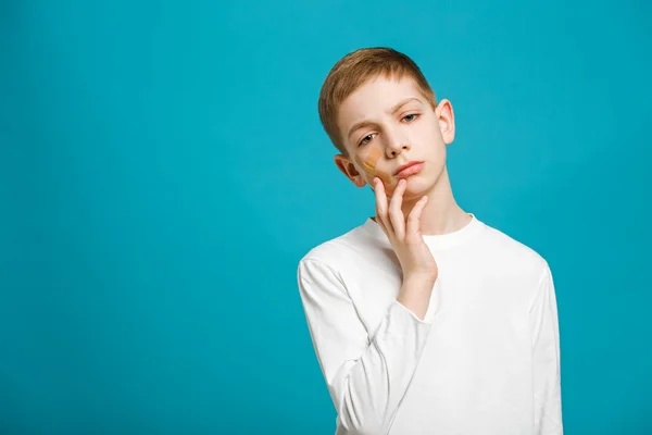 Unhappy boy with adhesive plaster on his cheek — Stock Photo, Image