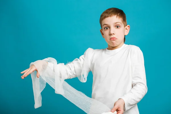 Verwirrter Junge in weißer Kleidung legt Verband an — Stockfoto