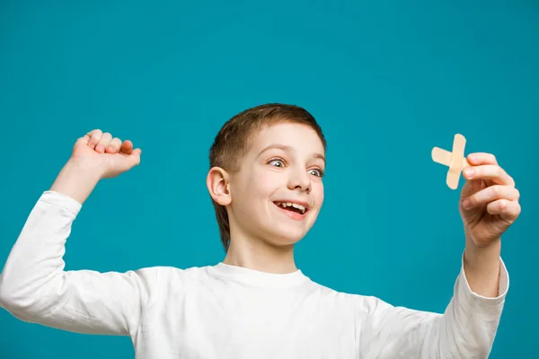 Gelukkige jongen met zelfklevende pleister kruis in zijn hand — Stockfoto