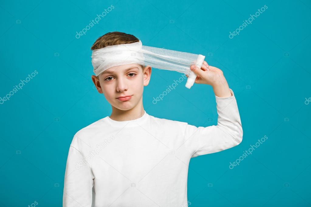 Portrait of unhappy boy taping up bandage on his head