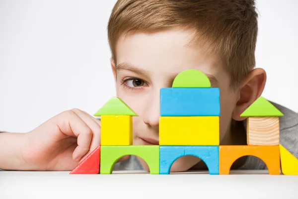 Ritratto di un ragazzo nascosto dietro una casa fatta di blocchi di legno — Foto Stock