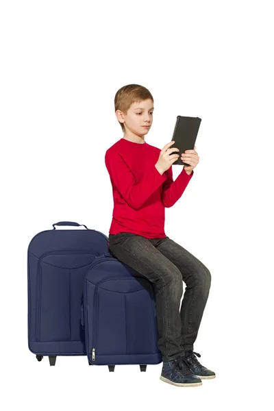 男孩坐在旅行袋使用绘图板上白色孤立 — 图库照片
