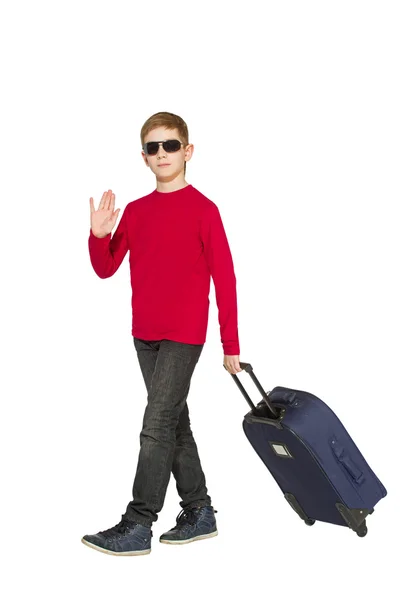 戴着墨镜，走路和挥动你好与旅行箱包的男孩 — 图库照片