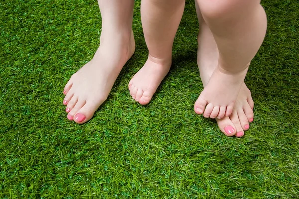 Yeşil çimenlerin üzerinde duran anne ve bebek bacakları — Stok fotoğraf