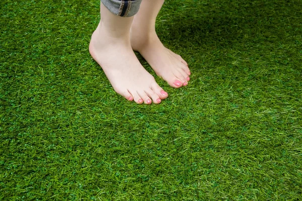 Yeşil çimenlerin üzerinde duran kadın bacakları — Stok fotoğraf
