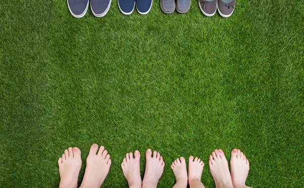Jambes familiales debout avec des chaussures sur l'herbe verte — Photo