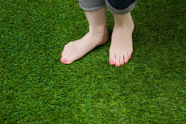 Woman legs in jeans stepping on grass — Stock Photo, Image