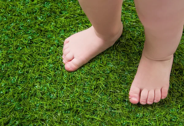 Bebê pernas nuas em pé na grama verde — Fotografia de Stock