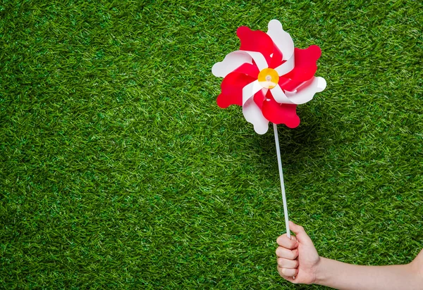 Menselijke hand pinwheel over gras met — Stockfoto