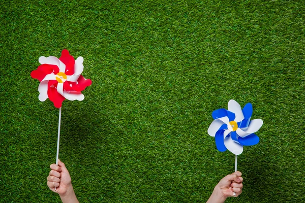 Emberi kéz, gazdaság pinwheels, fű alatt — Stock Fotó