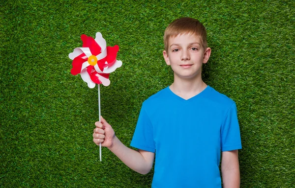 一个男孩抱着风车在草地的肖像 — 图库照片