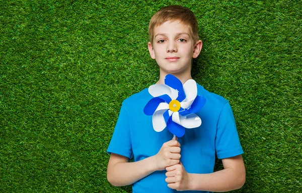 Portrait of a boy holding pinwheel over grass — Stock Photo, Image