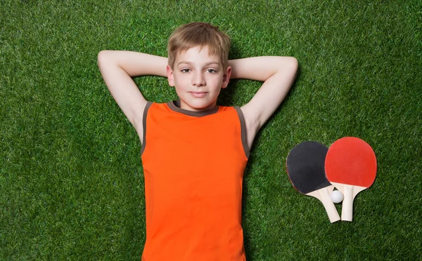 Niño acostado con raqueta de tenis sobre hierba verde —  Fotos de Stock