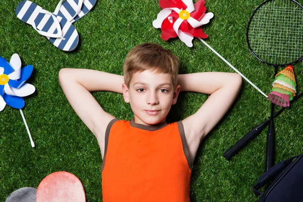 Junge liegt mit Sportgerät im Gras — Stockfoto