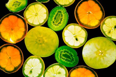 Obstscheiben auf einer schwarzen Flche, von hinten beleuchtet