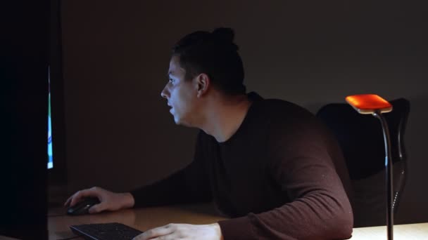 Νεαρός ομοφυλόφιλος με λεύκη εργάζεται μπροστά σε δύο οθόνη υπολογιστή. Σκοτεινό δωμάτιο.. — Αρχείο Βίντεο