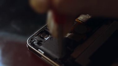 Tamirci akıllı telefonu tornavidayla söküyor. Bozuk telefonu tamir eden teknisyen, elektronik tamir servisi