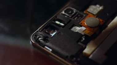 Tamirci akıllı telefonu tornavidayla söküyor. Bozuk telefonu tamir eden teknisyen, elektronik tamir servisi