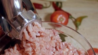 Kıyma kıyması, kıyma öğütücüsüne doğru kaydırılır. Et öğütücü çalışıyor ve mutfakta çiğ et kıvırıyor.