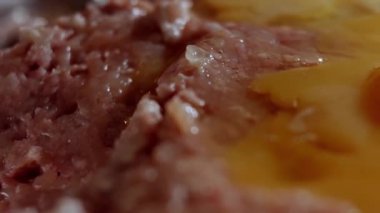 Metalik bir kasede taze kıymaya yumurta ekleme makrosu. Evde öğle yemeği pişiriyorum. Pirzola hazırlama süreci