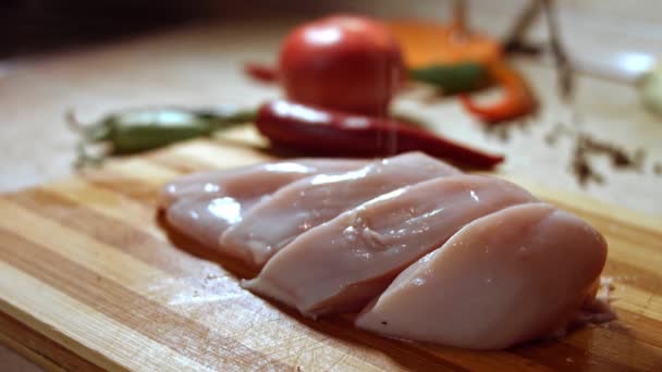 Close-up of raw chicken breast fillet being salted in a rustic wooden setting — Stock Video