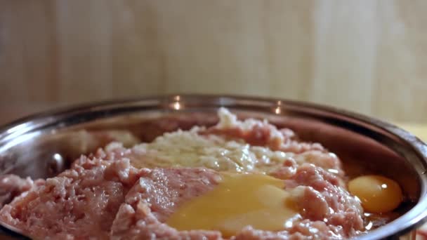 Primer plano de añadir huevos a la carne picada fresca en un tazón metálico. Cocinar el almuerzo en casa. Proceso de preparación de chuletas — Vídeos de Stock