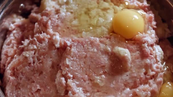 Primer plano de añadir huevos a la carne picada fresca en un tazón metálico. Cocinar el almuerzo en casa. Proceso de preparación de chuletas — Vídeos de Stock