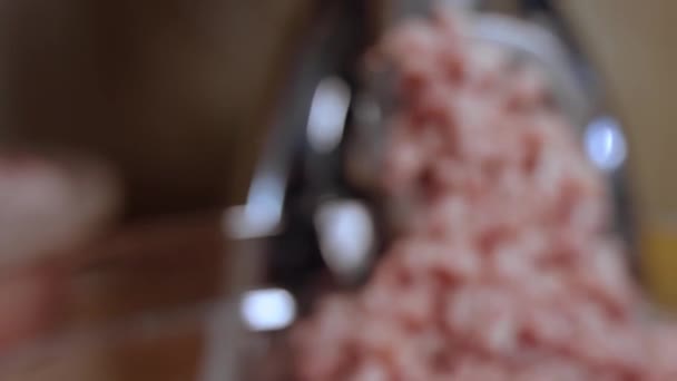 Closeup gehakt wordt door een zeef van een vleesmolen geschroefd. Vleesmolen werkt en wrijft rauw gehakt in de keuken — Stockvideo