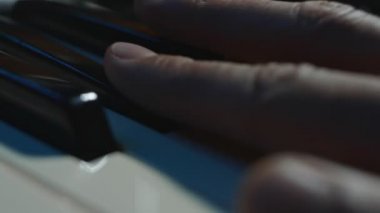 Piyanonun elektronik klavyesinde çalan el makrosu. Müzik stüdyosu konsepti. Stüdyoda müzisyen yapımcılığı şarkısı. Şarkı kaydetme işlemi. Zayıf ışık
