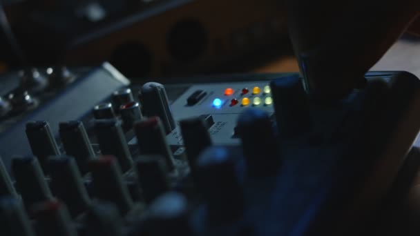 Gros plan des doigts ajustant la console de mixage sonore. console de mixage pour la production sonore en studio d'enregistrement. Pauvre lumière. Mouvement lent — Video