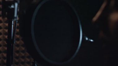 Profesyonel mikrofonlu yakışıklı rap şarkıcısının modern stüdyoda yeni şarkılar söylemesinin arka planında. Müzik prodüksiyonu. Zayıf ışık