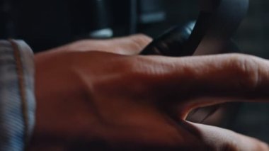 Yakışıklı rap şarkıcısının kafasına kulaklık takıp modern stüdyoda yeni şarkı kaydetmeye hazırlandığı Macro görüntüsü. Müzik prodüksiyonu. Zayıf ışık.