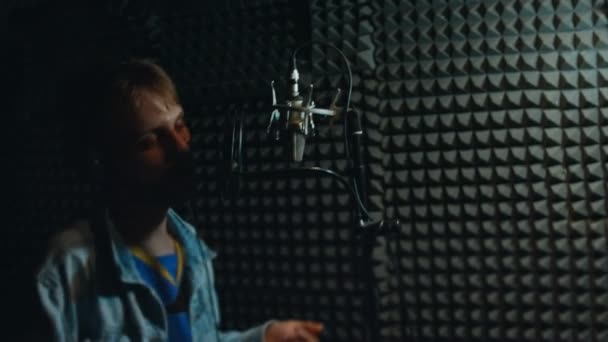Potret penyanyi rap pria tampan di headphone dengan mikrofon profesional menyanyikan lagu baru di studio modern. Produksi musik. Miskin cahaya — Stok Video