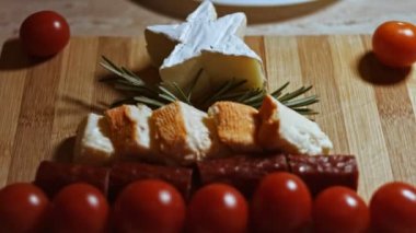 Düz peynir ve et tabağı. Noel ağacı şeklinde dizilmiş peynir, füme sosis, domates, zeytin ve rozmarin. Noel tatili için yemek. Makro görünüm