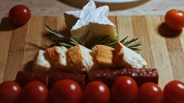 Pose plate de fromage et plateau de viande. Tranches de fromage, saucisse fumée, tomates, olives et rozmarine disposées en forme d'arbre de Noël. Nourriture pour Noël. Vue macro — Video