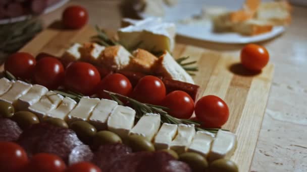 Platte kaas en vleesschotel. Stukjes kaas, gerookte worst, tomaten, olijven en rozmarin in de vorm van een kerstboom. Eten voor kerstvakantie. Langzame beweging — Stockvideo