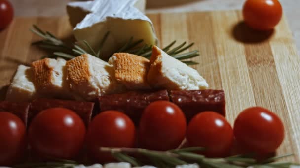 Platte kaas en vleesschotel. Stukjes kaas, gerookte worst, tomaten, olijven en rozmarin in de vorm van een kerstboom. Eten voor kerstvakantie. Langzame beweging — Stockvideo