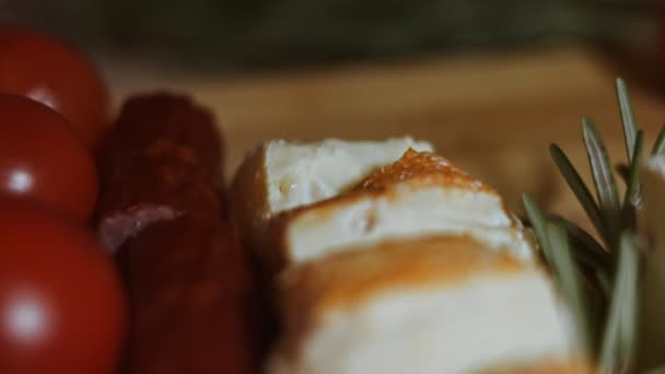 Płaskie ułożenie sera i talerza mięsa. Kawałki sera, wędzonej kiełbasy, pomidorów, oliwek i rozmarynu ułożone w kształt choinki. Jedzenie na święta. Widok makro — Wideo stockowe