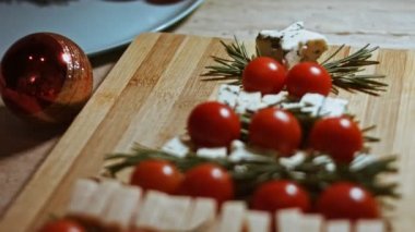 Peynir ve domates düzlüğü. Noel ağacı şeklinde dizilmiş peynir, domates ve rozmarin dilimleri. Noel tatili için yemek. Döndürme. Yavaş çekim