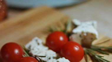 Peynir ve domates düzlüğü. Noel ağacı şeklinde dizilmiş peynir, domates ve rozmarin dilimleri. Noel tatili için yemek. Yavaş çekim, makro görünüm