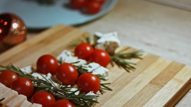 Plat leggen van kaas en tomaten. Stukjes kaas, tomaten en rozmarin in de vorm van een kerstboom. Eten voor kerstvakantie. Rotatie. Langzame beweging — Stockvideo