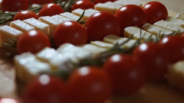 Plat leggen van kaas en tomaten. Stukjes kaas, tomaten en rozmarin in de vorm van een kerstboom. Eten voor kerstvakantie. Langzame, macro-view — Stockvideo