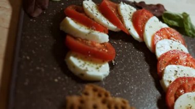 Caprese - İtalyan ulusal yemeği. Noel şeker kamışı şeklinde dilimlenmiş domates ve mozarella. Fesleğen ve zeytinyağıyla servis edilir. Yavaş çekimde. Makro görünüm