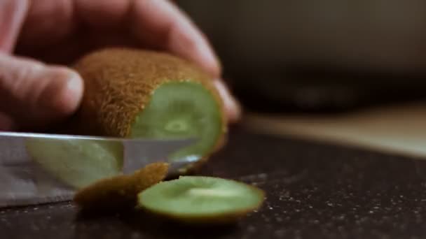 Pelando un jugoso kiwi verde sobre una tabla de cortar de mármol negro. Cronograma — Vídeo de stock