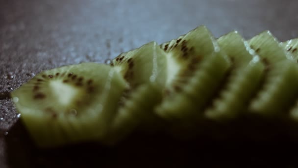 Tranches de kiwi frais juteuses sur une planche à découper en marbre noir. Vue macro. Mouvement lent — Video